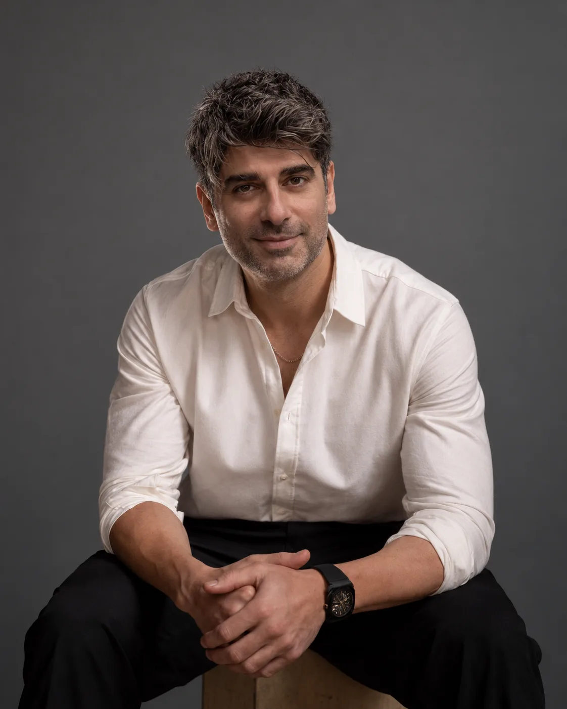 Pouya Ramzi in a white shirt, seated and smiling at the camera