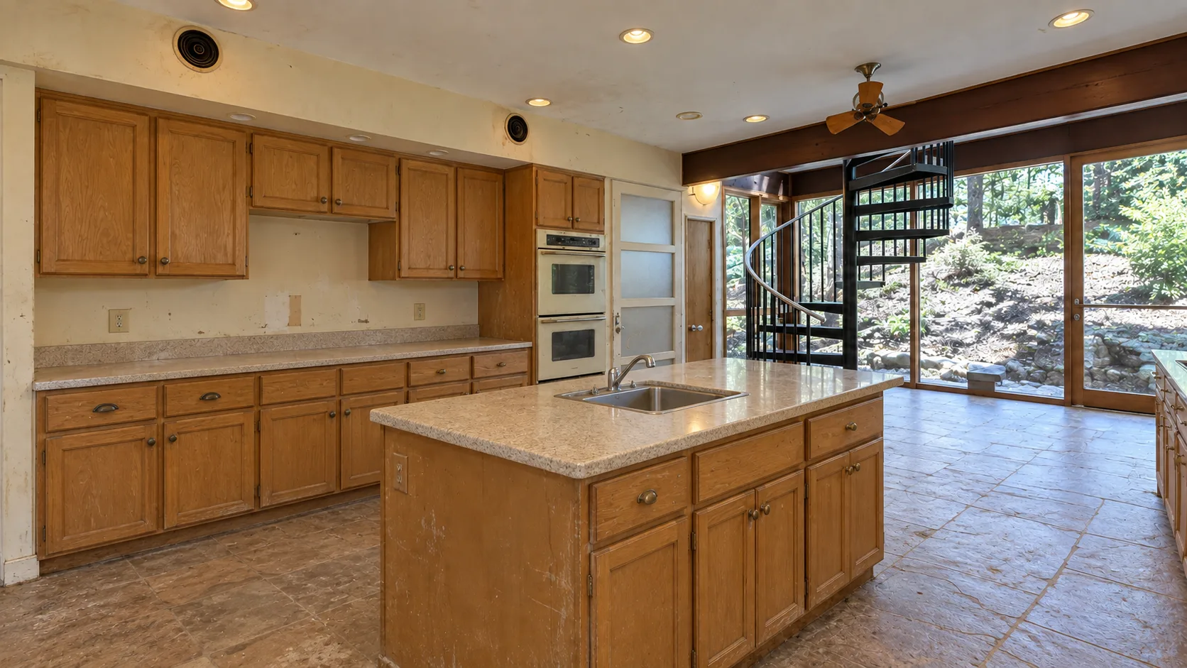 Kitchen before renovation, with oak cabinets, laminate countertops and a small island