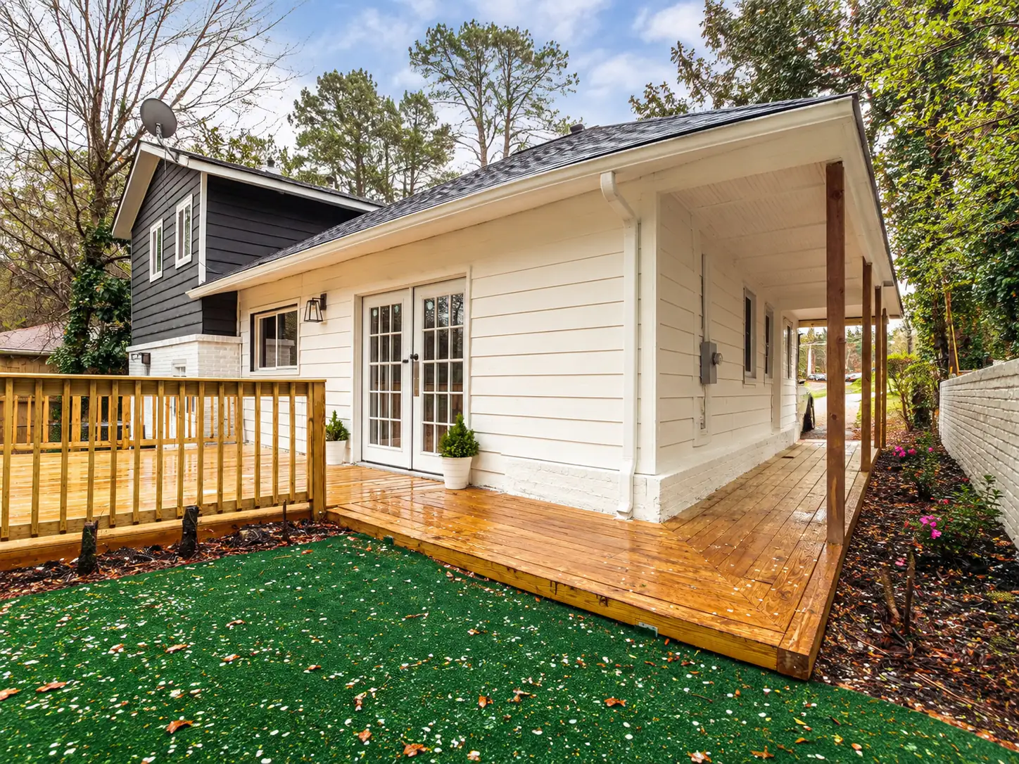 Design concept of the same cottage, with a wood deck in place of the pavers wrapping under the covered side walk, a railed raised deck and turf in front